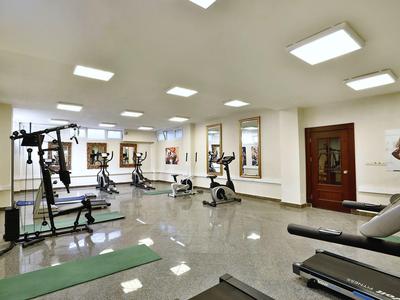 Geräumiger Fitnessraum mit modernen Trainingsgeräten, glänzendem Boden und hellen Deckenleuchten.