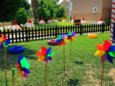 Bunter Garten mit mehreren Windrädern aus Plastik vor einem Zaun und kleinen Spielzelten dahinter.