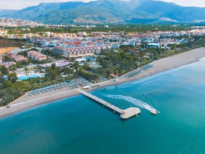 Aerial view of a long pier extending into the calm blue sea in front of a coastal town.