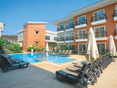 Hotel with outdoor pool, surrounded by sun loungers and umbrellas in sunny weather.