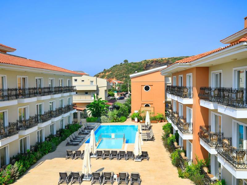 Hotel with two buildings, swimming pool, and sun loungers between them on a sunny day