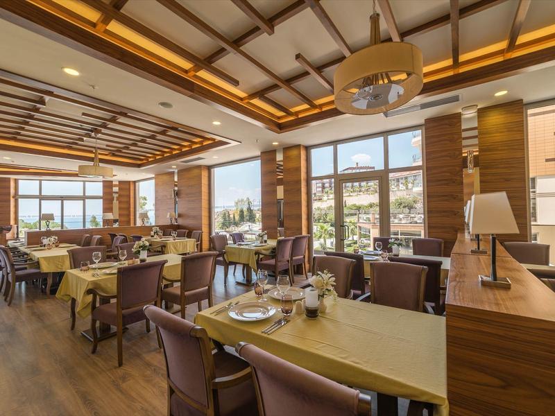 Ristorante luminoso e moderno con mobili in legno e grandi finestre con vista sulla città.