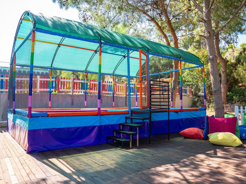 Trampolino colorato coperto su pavimento in legno all'aperto accanto agli alberi.