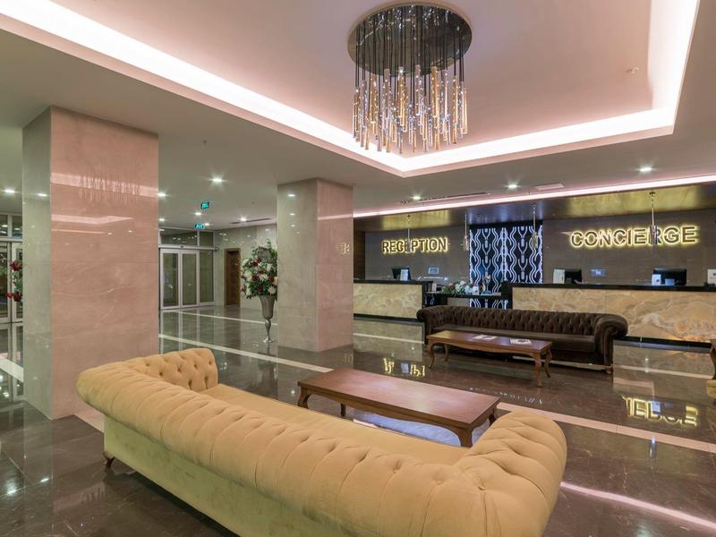 Area lobby moderna dell'hotel con divani, tavolini e banco reception illuminato.