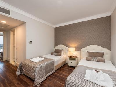 Modernes Schlafzimmer mit zwei Einzelbetten, Holzboden, Nachttisch und stimmungsvoller Beleuchtung.