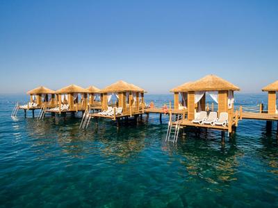 Bungalow sull'acqua con tetti di paglia su acqua di mare limpida sotto un cielo blu.