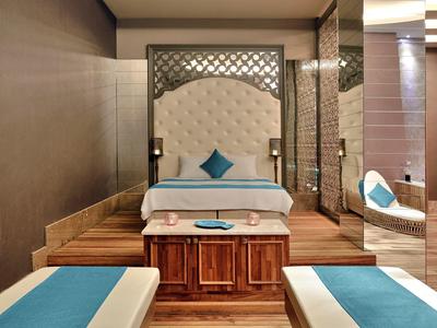 Modernes Schlafzimmer mit weißen und blauen Betten, hölzernen Möbeln und dekorativer Wandgestaltung.