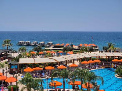 Ampia area piscina con ombrelloni arancioni e vista mare in un resort.