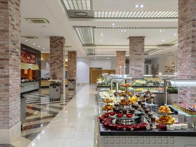 Moderner Frühstücksbereich mit Buffet, LED-Beleuchtung, Glasvitrinen und Marmorboden.