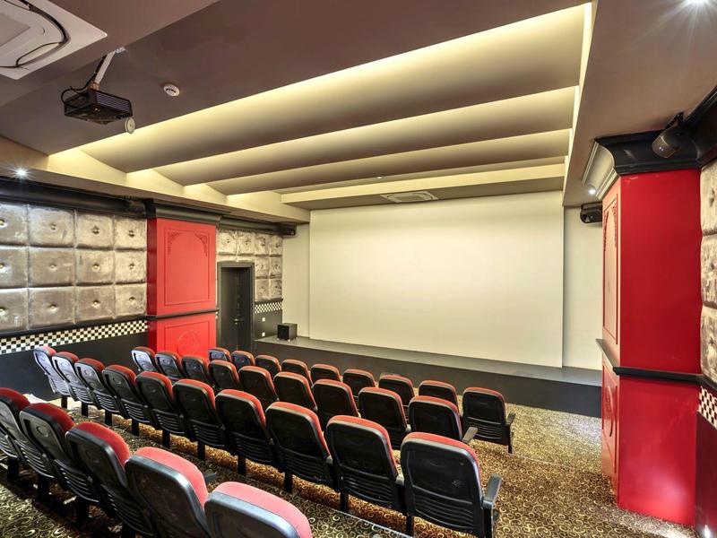 Kleines Heimkino mit roten Sitzen, weißer Leinwand, gepolsterten Wänden und gedämpftem Deckenlicht.