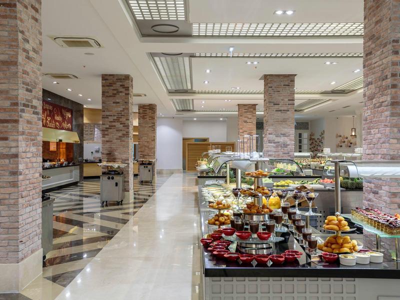 Moderner Frühstücksbereich mit Buffet, LED-Beleuchtung, Glasvitrinen und Marmorboden.