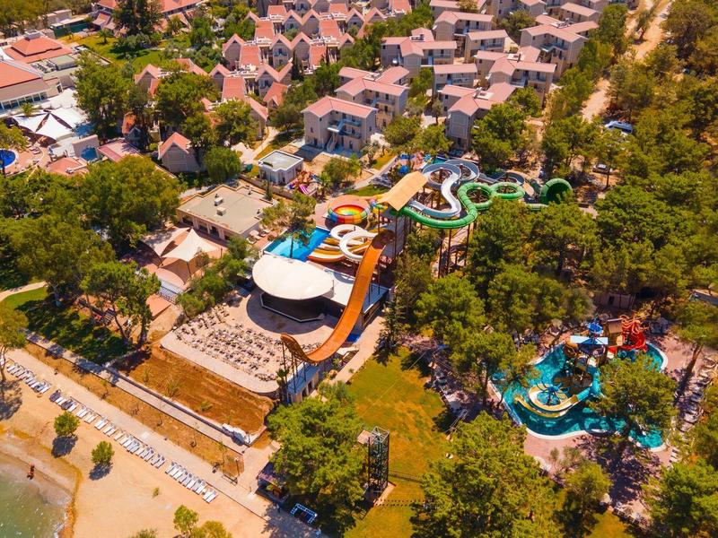 Freizeitpark mit Wasserrutschen, Schwimmbädern und umgeben von Bäumen nahe Strandpromenade.