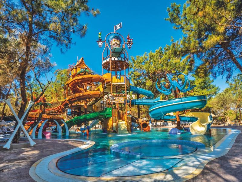 Wasserspielplatz mit Rutschen, Pool, Bäumen und blauen Himmel im Freien.