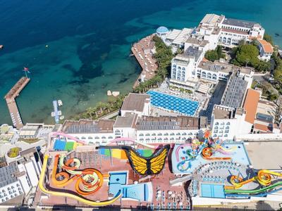 Luftaufnahme eines Resorts an der Küste mit Pools, Wasserrutschen und direktem Zugang zum Meer.