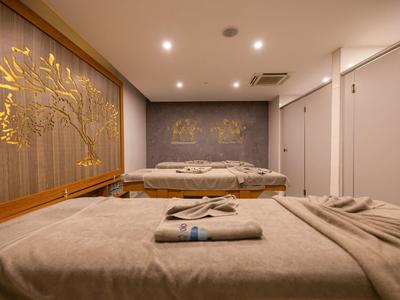 Gemütlicher Massageraum mit zwei Liegen, warmem Licht und dekorativen Wandkunstwerken