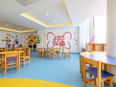 Kinderfreundlicher Spielraum mit bunten Stühlen, Tischen und Wanddekoration in hellem Raum