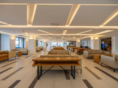 Moderner, großzügiger Hotellobby-Bereich mit stilvollen Sitzmöbeln und indirekter Deckenbeleuchtung.