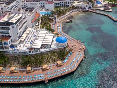 Hotel mit Terrasse, Liegestühlen und Pool direkt an klarem Meerwasser