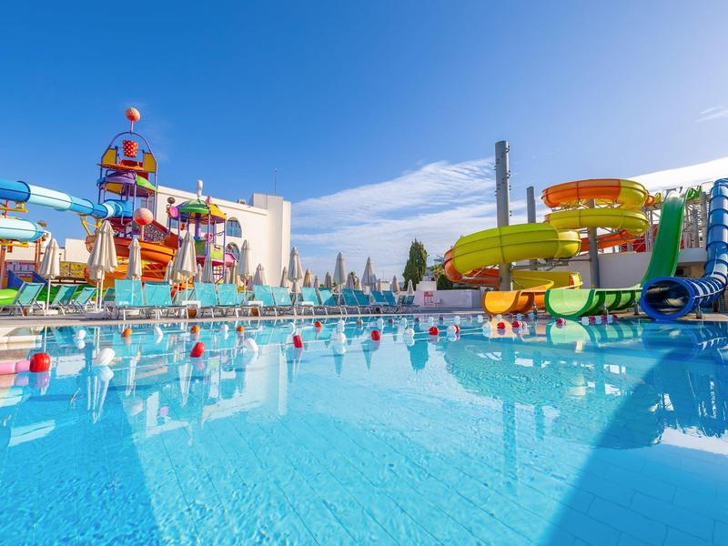 Wasserpark mit bunten Wasserrutschen und klarem blauen Pool unter strahlend blauem Himmel