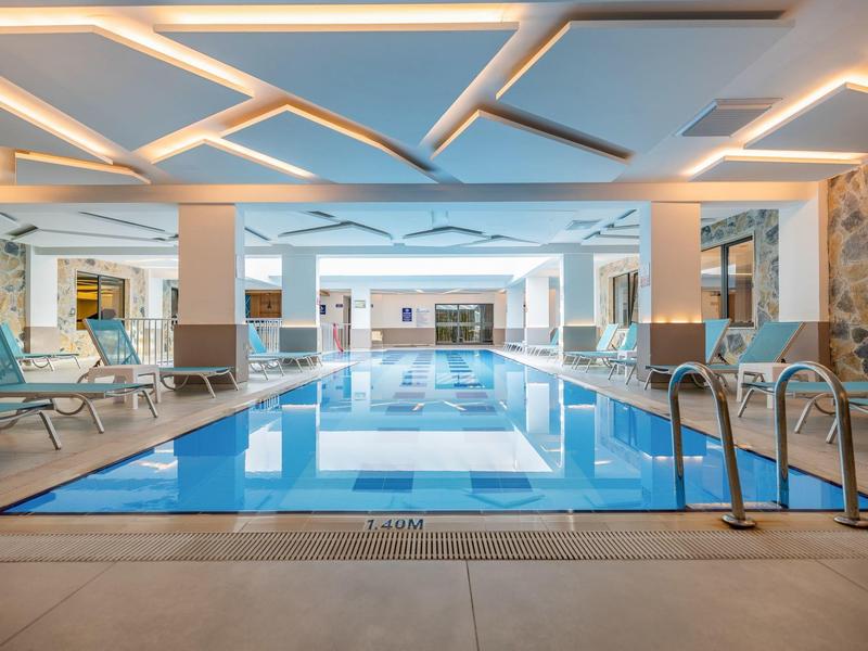 Moderner Innenpool mit Liegestühlen und indirekter Beleuchtung an der Decke.