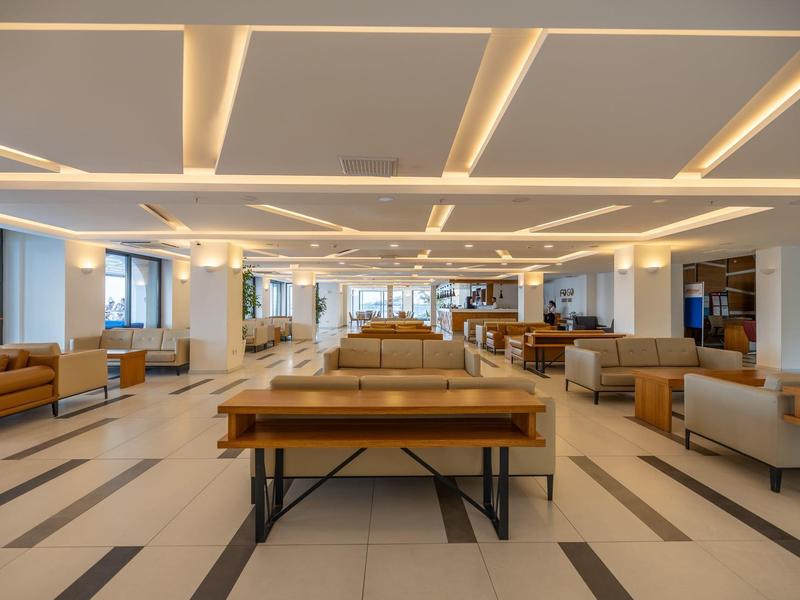 Moderner, großzügiger Hotellobby-Bereich mit stilvollen Sitzmöbeln und indirekter Deckenbeleuchtung.