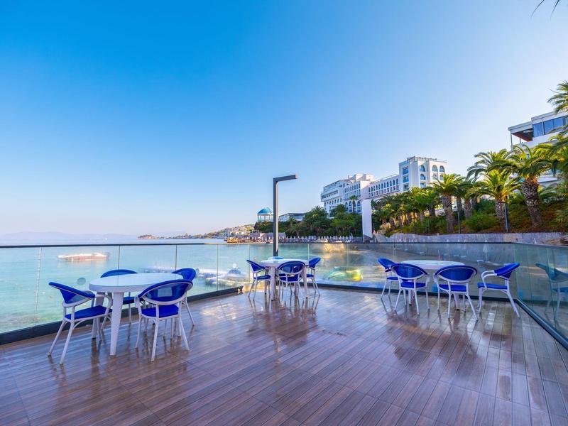 Terrasse mit blauen Stühlen und Tischen mit Meerblick bei sonnigem Wetter