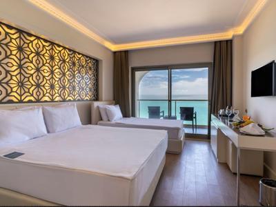 Modern hotelkamer met twee bedden, zeezicht en balkon.