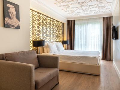Moderne hotelkamer met tweepersoonsbed, fauteuil en decoratief wandontwerp.