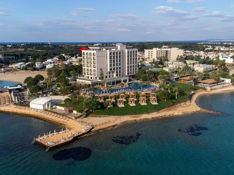 Letecký pohled na velký plážový hotel s moly a lehátky na pobřeží.
