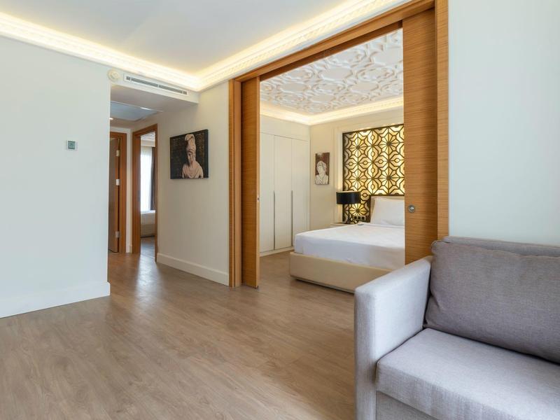 Moderní hotelový pokoj s dřevěnými podlahami, bílými stěnami a pohodlným posezením.