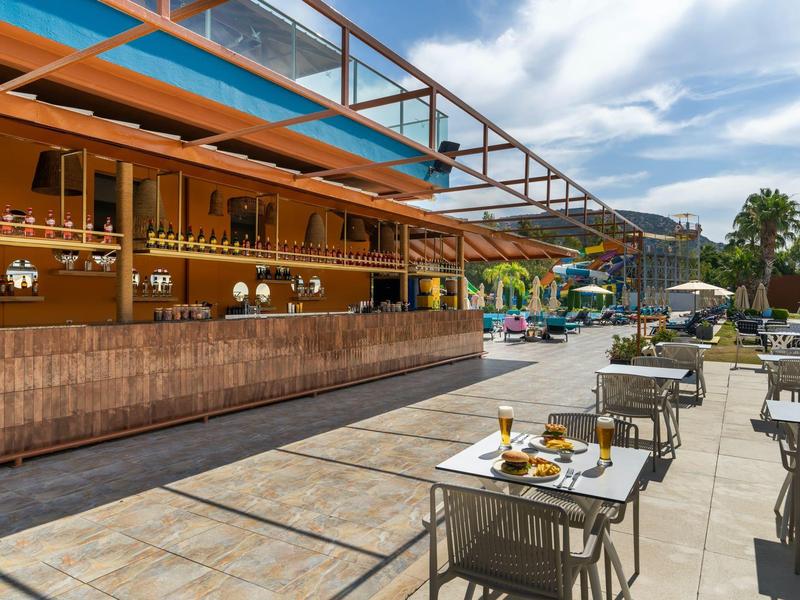 Outdoor terrace dining area with tables set for breakfast under a partly cloudy sky.