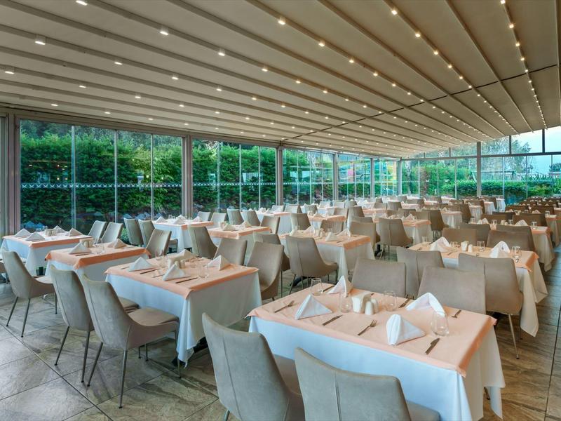 Spacious covered outdoor dining area with beige chairs and neatly set tables.