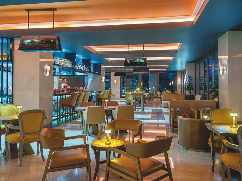 Modern hotel lounge with wooden tables, cozy chairs, and blue accent walls.