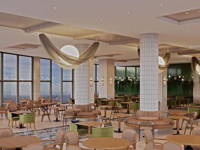 Ampia sala da pranzo moderna dell'hotel con tavoli rotondi, sedie e colonne piastrellate bianche.