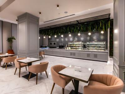 Ristorante di hotel moderno con sedie grigie e decorazioni di piante sospese verdi.