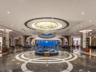 Lussuosa hall d'hotel con grande acquario, area salotto circolare e lampadario al soffitto.