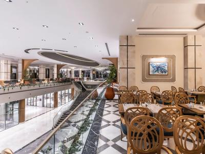 Area hotel di lusso con zona pranzo e vista aperta su una galleria.