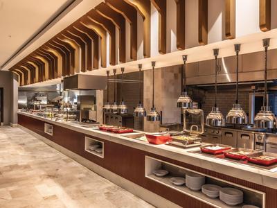 Lunga area buffet in un ristorante d'hotel dal design elegante con illuminazione calda e decorazioni moderne.