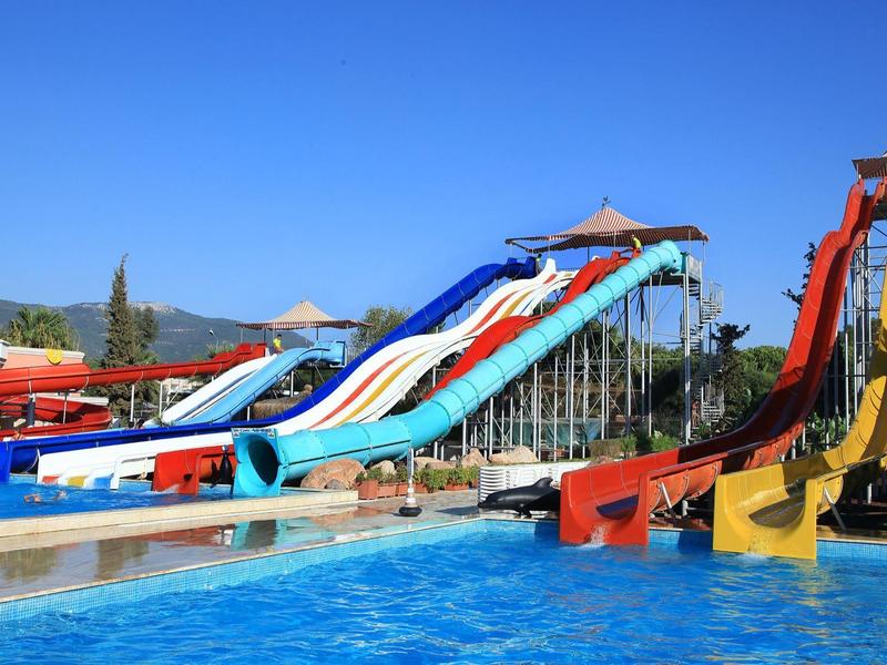 Bunte Wasserrutschen über einem klaren Schwimmbecken unter blauem Himmel in einem Wasserpark.