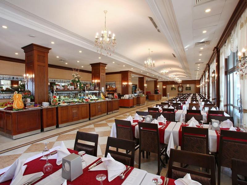 Elegantes Restaurant mit dunklen Holzmöbeln, weißen Tischdecken und rot-weißen Servietten.