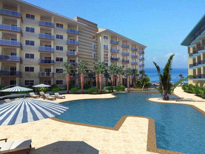 Basen na świeżym powietrzu z parasolami i leżakami między dwoma budynkami hotelowymi pod błękitnym niebem.