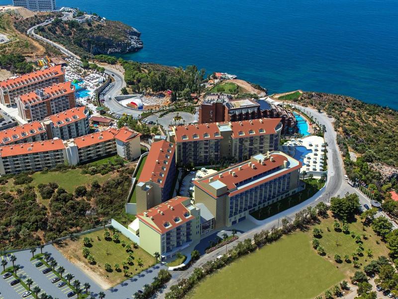 Kompleks hotelowy z wieloma budynkami z czerwonymi dachami nad morzem.