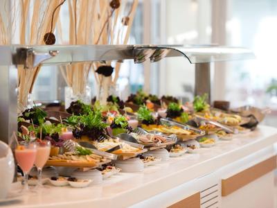 Buffet elegante con insalate fresche e antipasti su vassoi in una sala da pranzo luminosa.