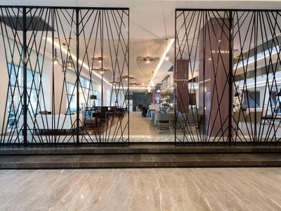 Lobby di hotel moderna con schermo metallico geometrico nero decorativo e pavimento in legno lucido.