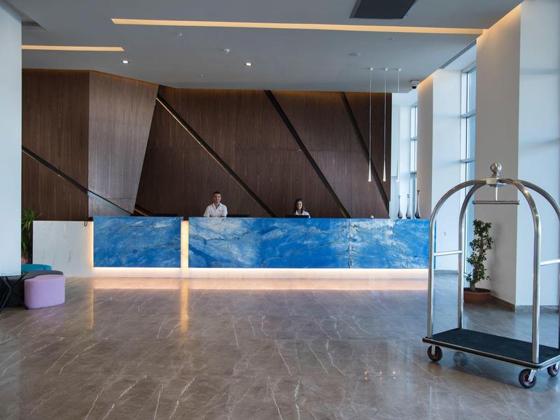 Reception d'hotel moderna con banco in marmo blu, pannelli in legno e carrello bagagli