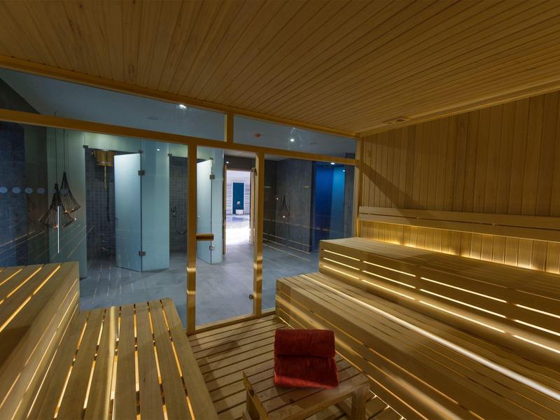 Sauna moderna in legno con porta in vetro e illuminazione calda e luminosa.