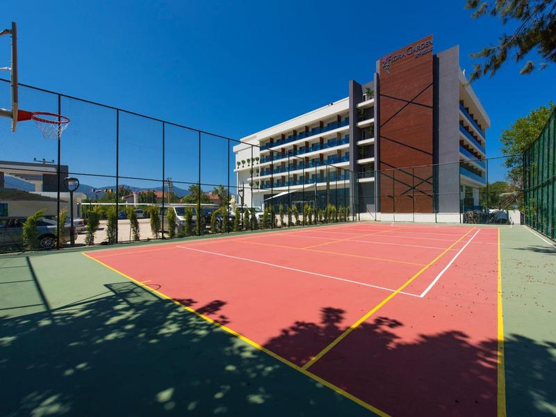 Campo da basket all'aperto accanto a un edificio di hotel moderno sotto un cielo azzurro.