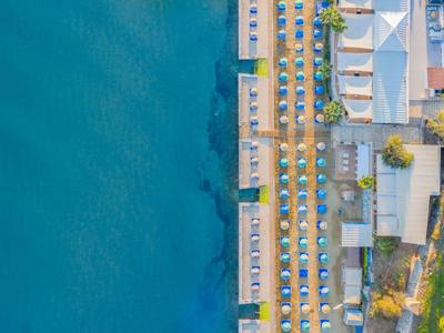 Letecký pohled na plážové letovisko s deštníky a čistou modrou vodou