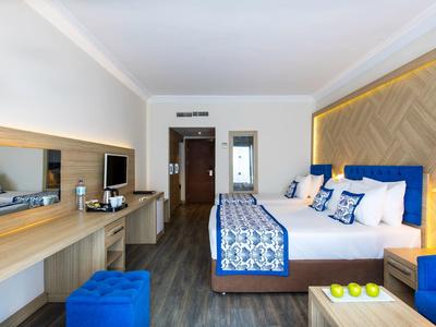 Moderní hotelový pokoj s manželskou postelí, modrobílým povlečením a psacím stolem se zrcadlem