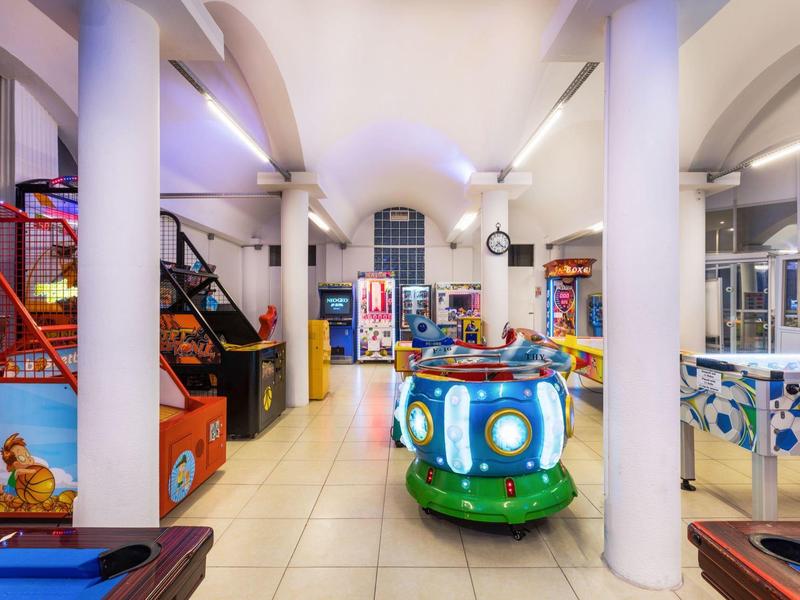 Interiér herní zóny v hotelu s arkádovými automaty a zábavními zařízeními.